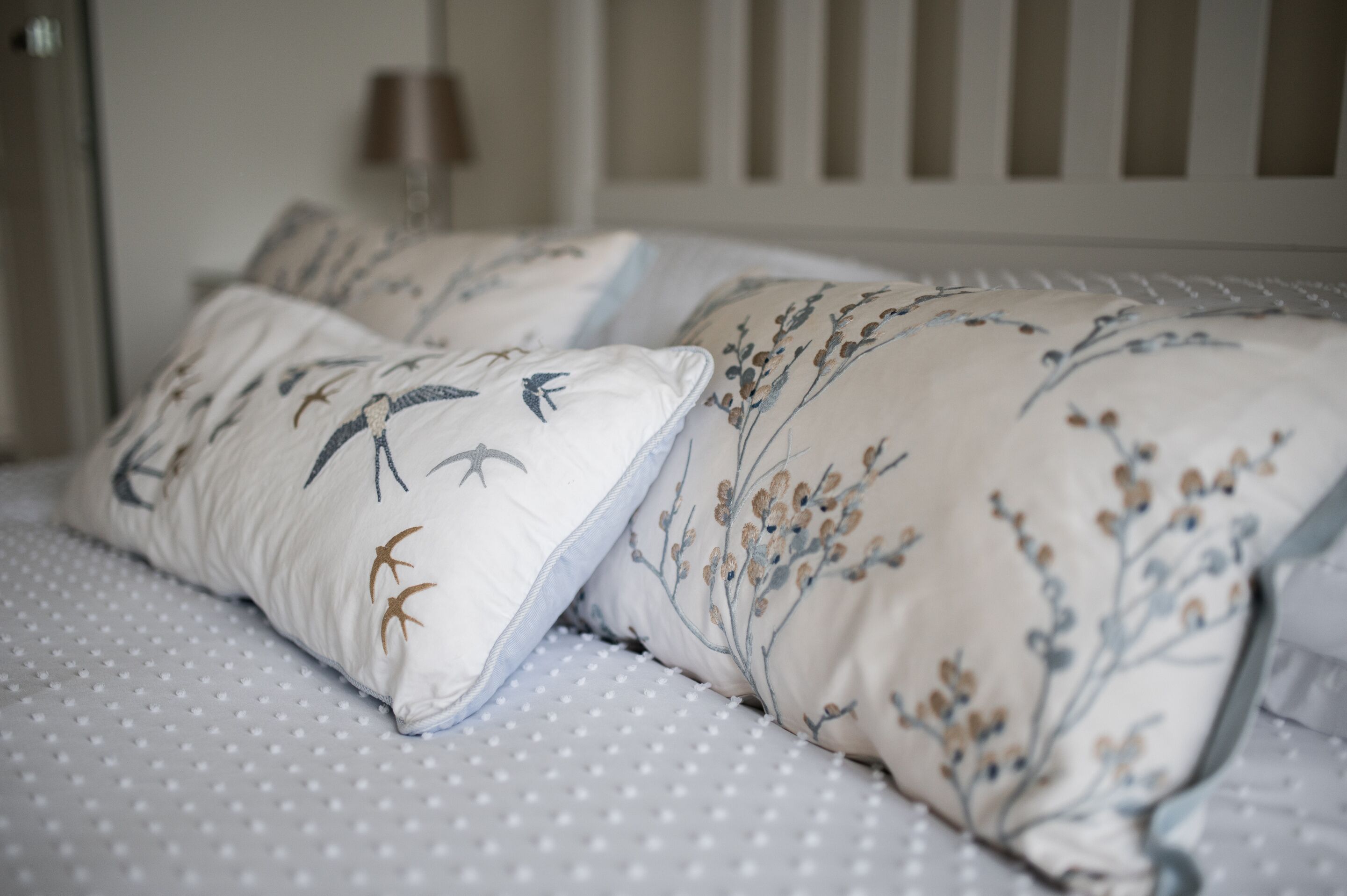 A bed with white bedding and floral-patterned pillows.