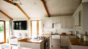 Una cocina moderna con armarios blancos, una isla de madera y un ventanal grande.