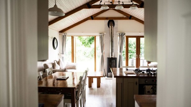 Una cocina acogedora con una mesa de madera, sillas, una estufa y un ventanal con cortinas.