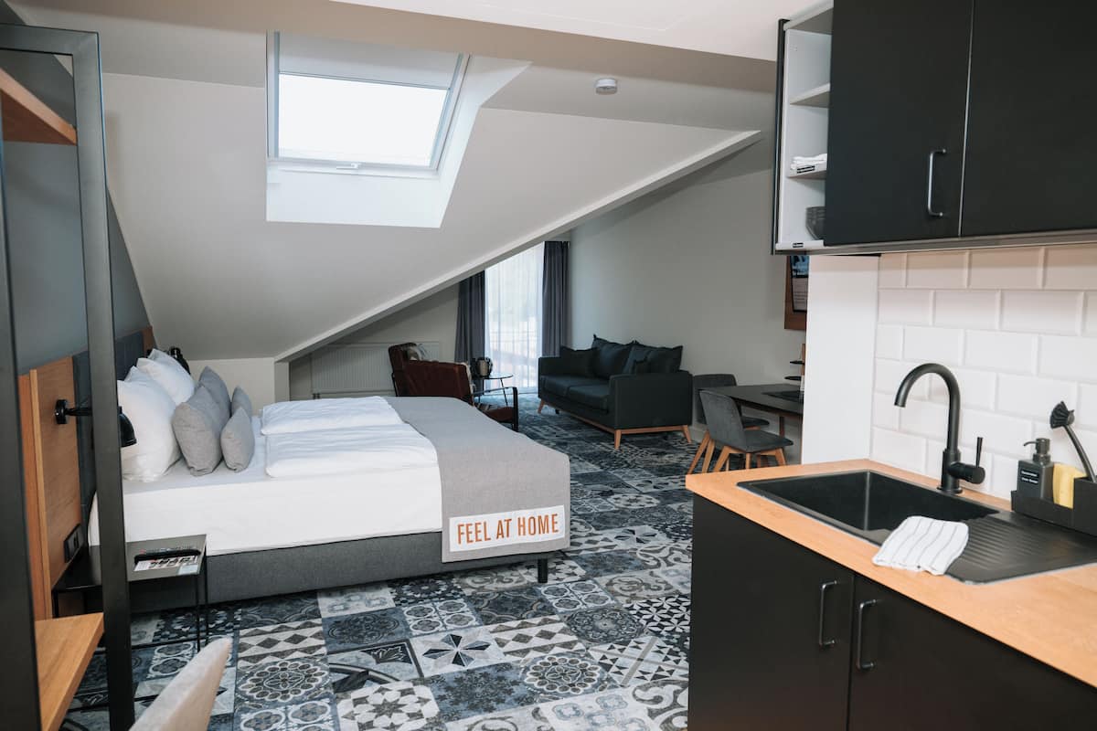 A compact, modern room with a loft bed, a small kitchenette, and a dining area.
