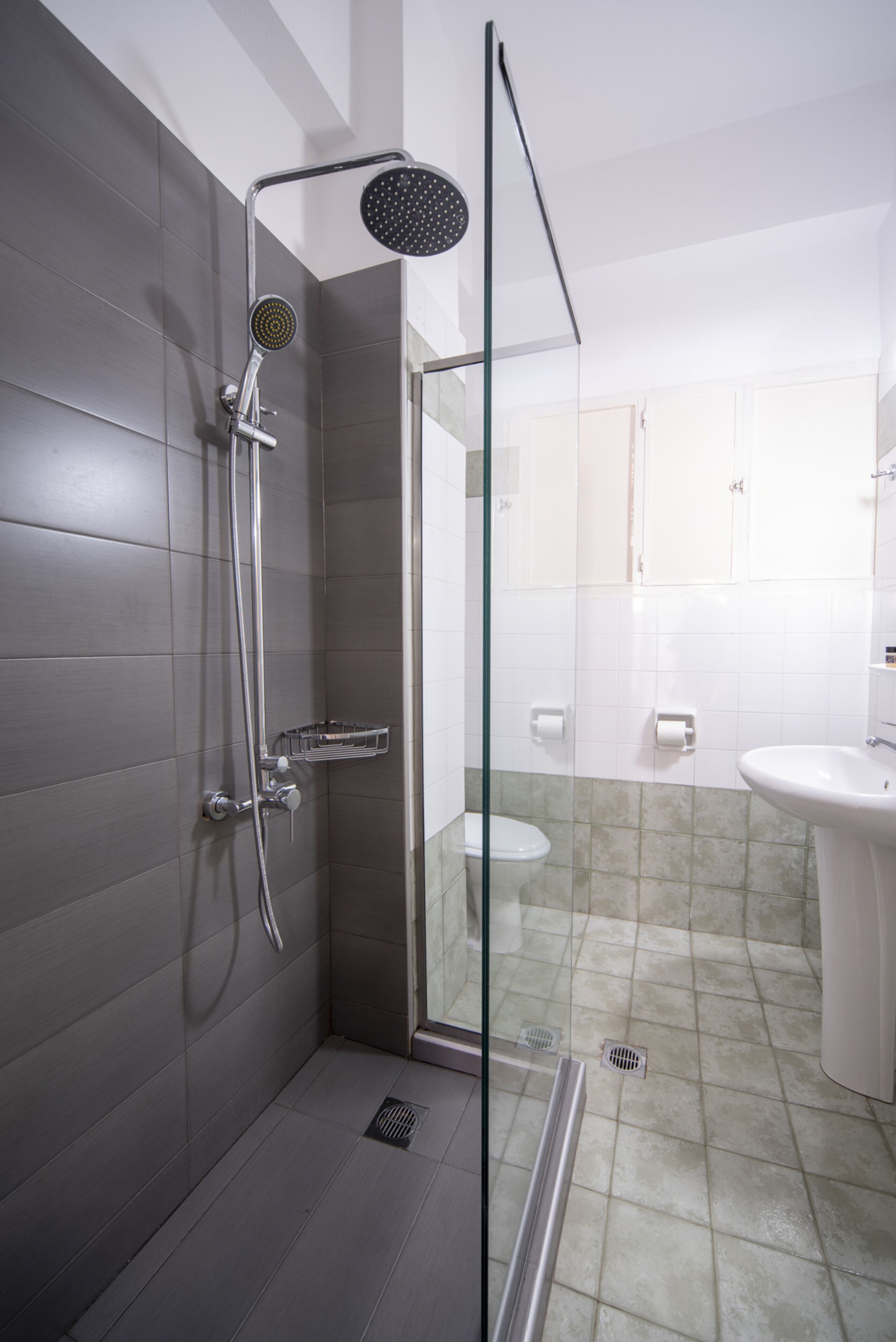 A modern bathroom with a glass shower enclosure, a white sink, and a toilet.