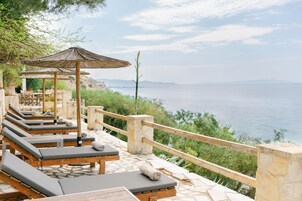 Terraza frente al mar con sillones de descanso y una pérgola de madera, con vistas al océano.