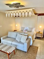 Quarto moderno com cama, sofá, mesinha e luminária de teto diferenciada.