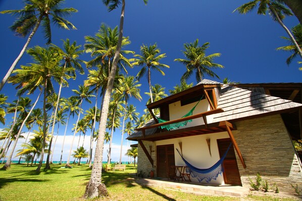 A beachfront property with a wooden structure, a hammock, and palm trees. - Pontal dos Carneiros Beach Bungalows (Tamandaré)