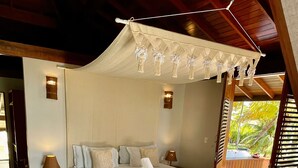 A spacious bedroom with a large bed, two bedside tables, a nightstand, and a canopy bed. - Pontal dos Carneiros Beach Bungalows (Tamandaré)