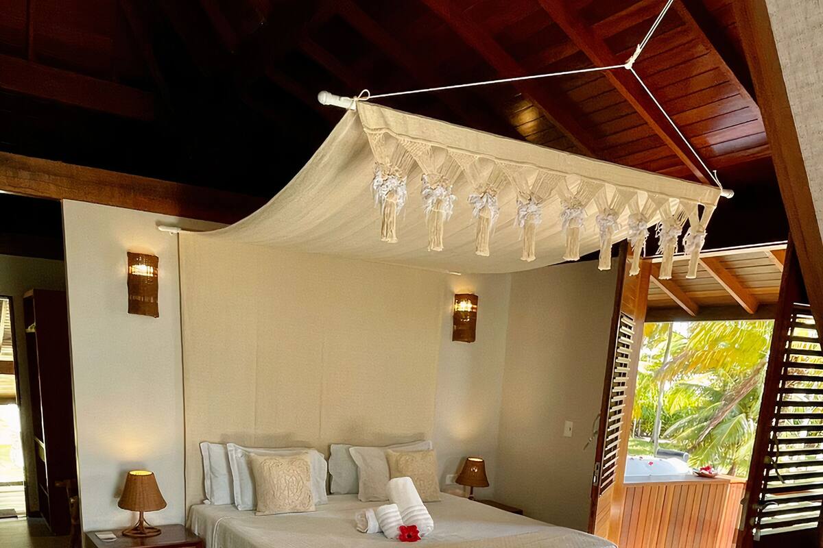 A spacious bedroom with a large bed, two bedside tables, a nightstand, and a canopy bed.