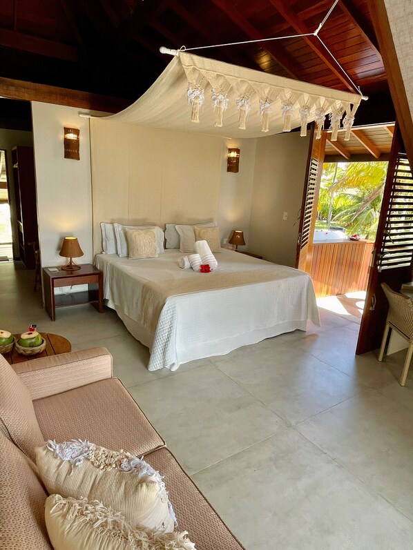 A spacious bedroom with a large bed, two bedside tables, a nightstand, and a canopy bed. - Pontal dos Carneiros Beach Bungalows (Tamandaré)