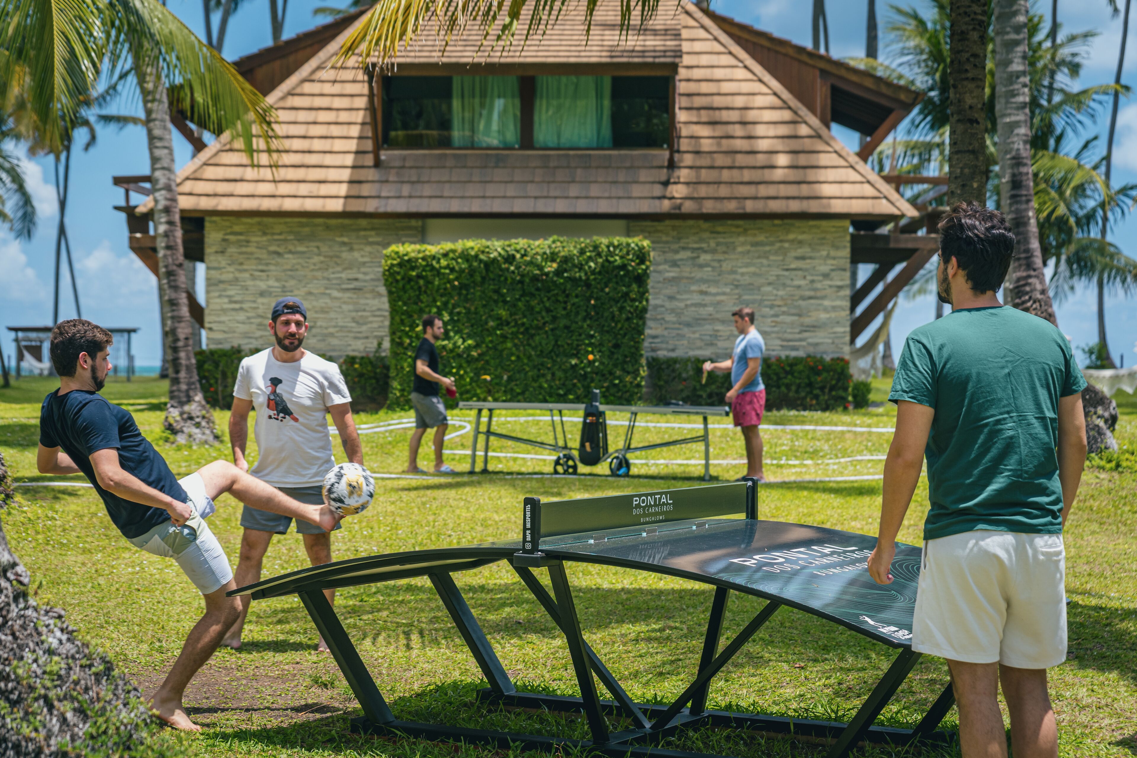 A group of people playing soccer on a grassy field with a tennis table in the foreground.