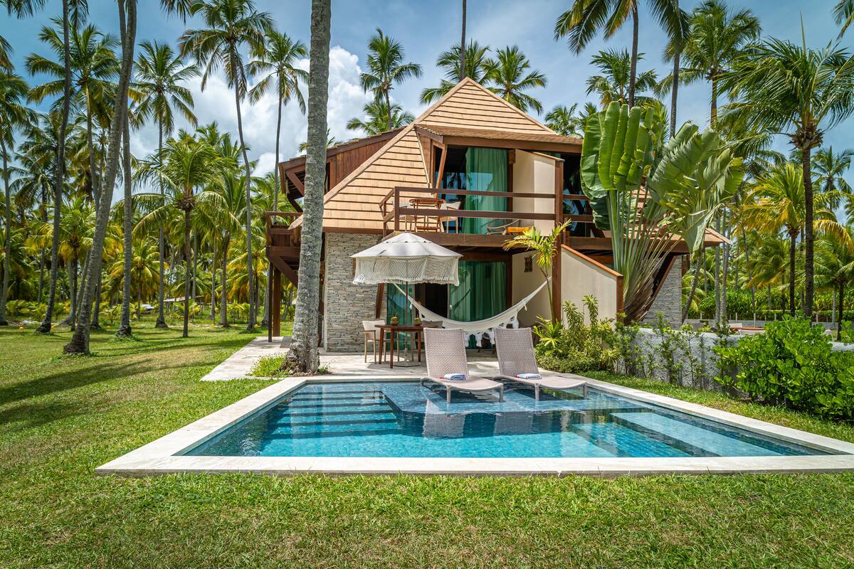 A modern resort with a pool, lounge chairs, and a hammock.