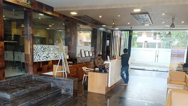 Zona de recepción de un hotel con una escalera de mármol, un mostrador de recepción y un área de espera con sillones.