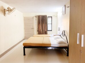 Un dormitorio con cama, armario, ventana con cortinas y ventilador de pared.