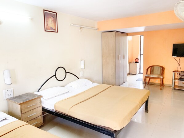 Una habitación de hotel con cama, mesita de noche, armario y televisor.