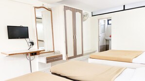 Habitación de hotel con dos camas, televisión, espejo y baño visible a través de una puerta abierta.