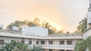 Un edificio de varios pisos con un patio, asientos al aire libre y áreas verdes.