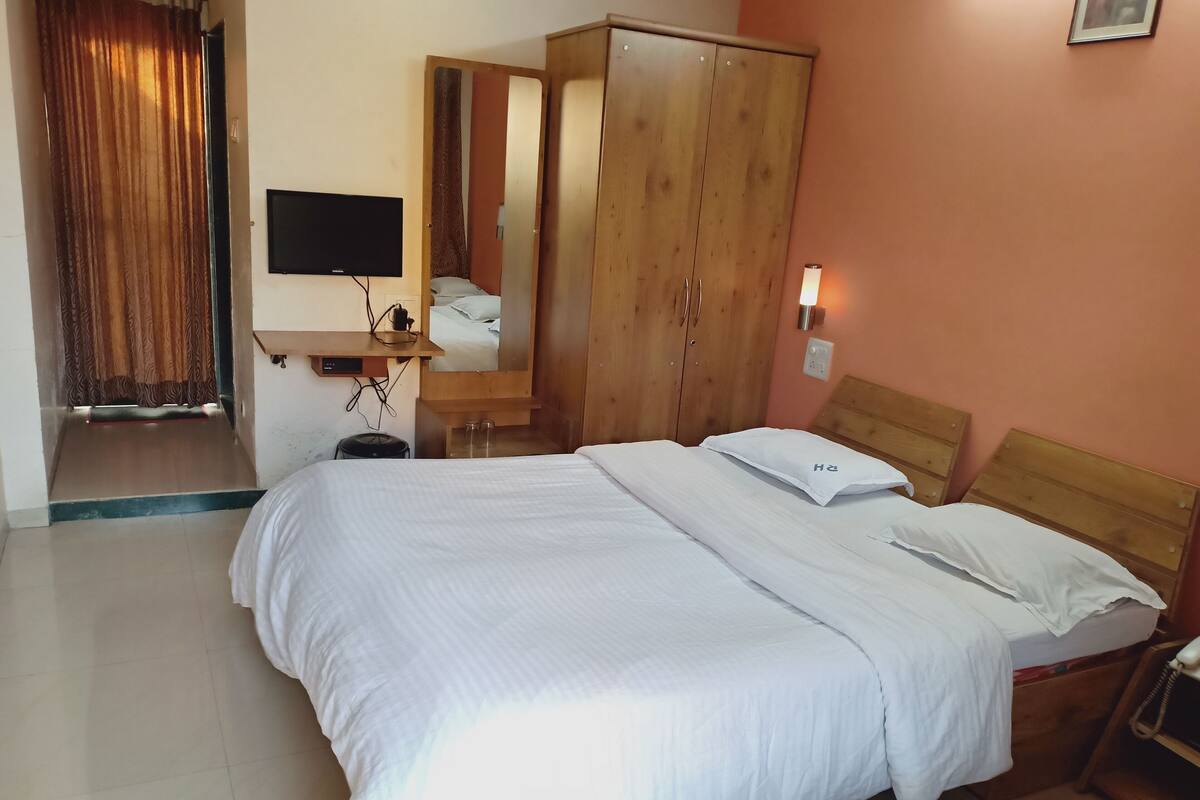 Een slaapkamer met een bed, een kledingkast, een televisie en een bedlamp.