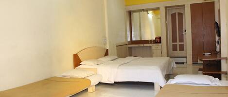 A hotel room with two beds, a bench, a desk, and a mirror.