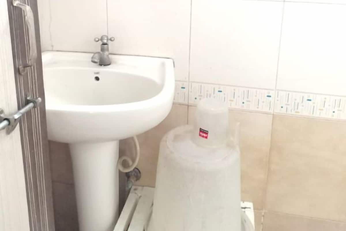 Een badkamer met een wit wastafelmeubel, een spiegel erboven en een betegelde muur.