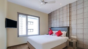 Ein Schlafzimmer mit einem großen Bett, einem an der Wand montierten Fernseher und einem Fenster mit Blick auf Gebäude.