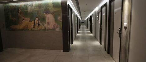 A long, narrow hallway with doors on one side and a mural on the other.