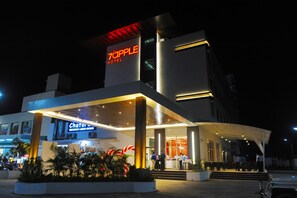 Een modern hotel met een opvallend bord waarop '7APPLE HOTEL' staat, en een zichtbare entree met treden die naar de deur leiden.