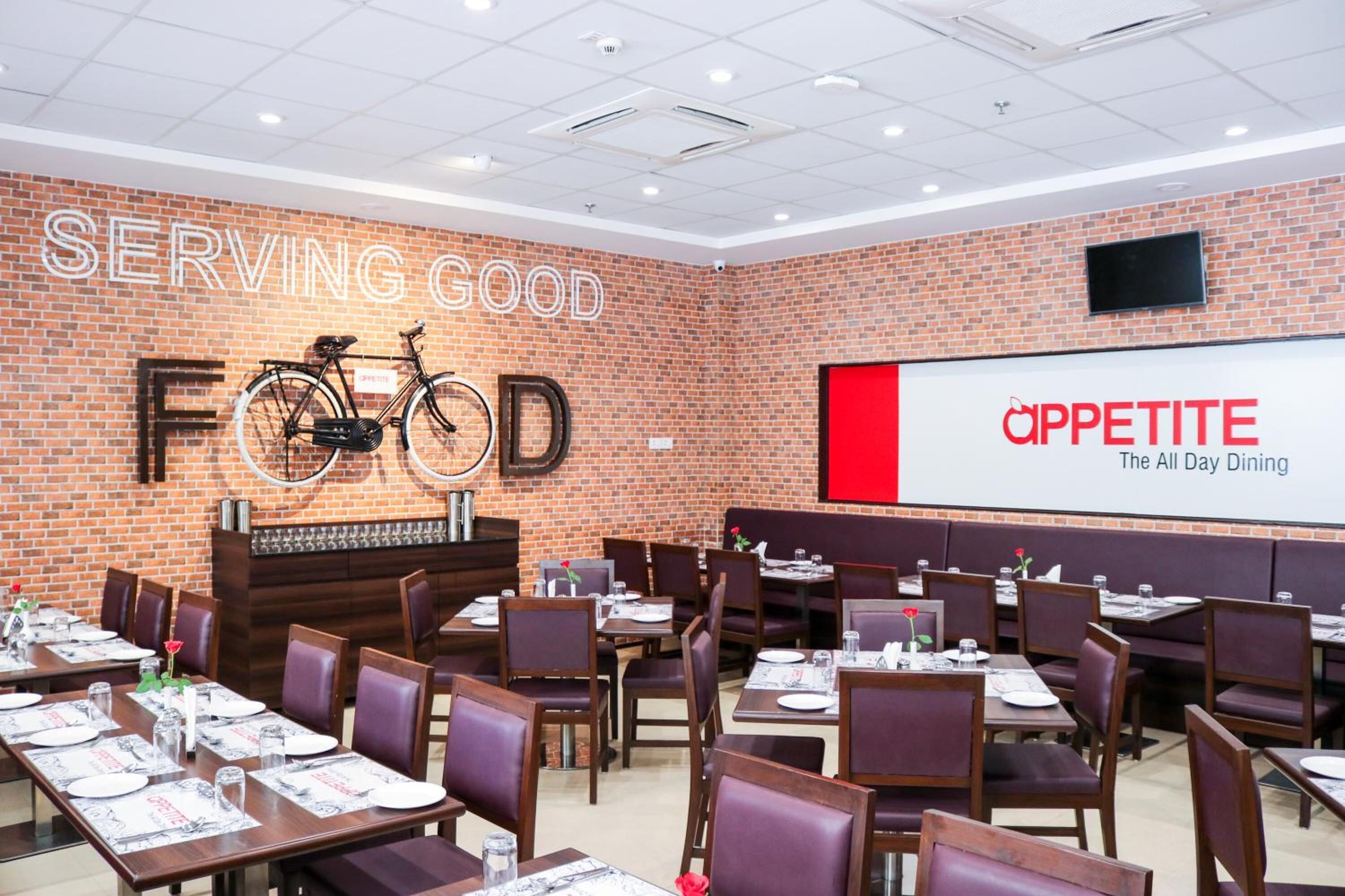 A restaurant with brick walls, wooden tables, and purple chairs.