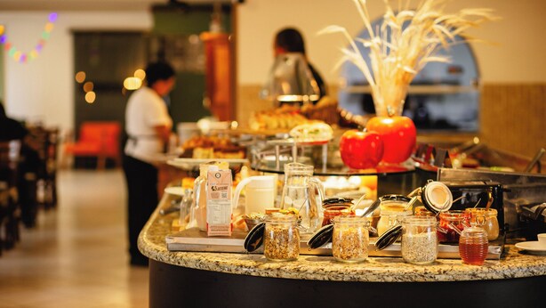 A buffet counter with various food items and condiments. - Hotel Ferraz (Pouso Alegre)