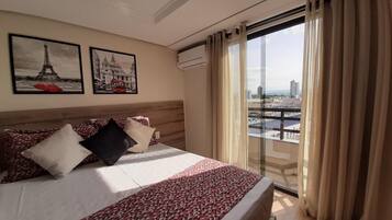 A hotel room with a bed, a cityscape view, and two framed pictures on the wall.
