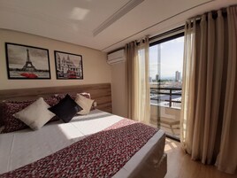 Una habitación de hotel con una cama, vistas de la ciudad y dos cuadros en la pared.