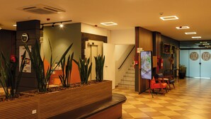 A reception area with a checkered floor, a reception desk, a staircase, and a seating area with chairs. - Hotel Ferraz (Pouso Alegre)