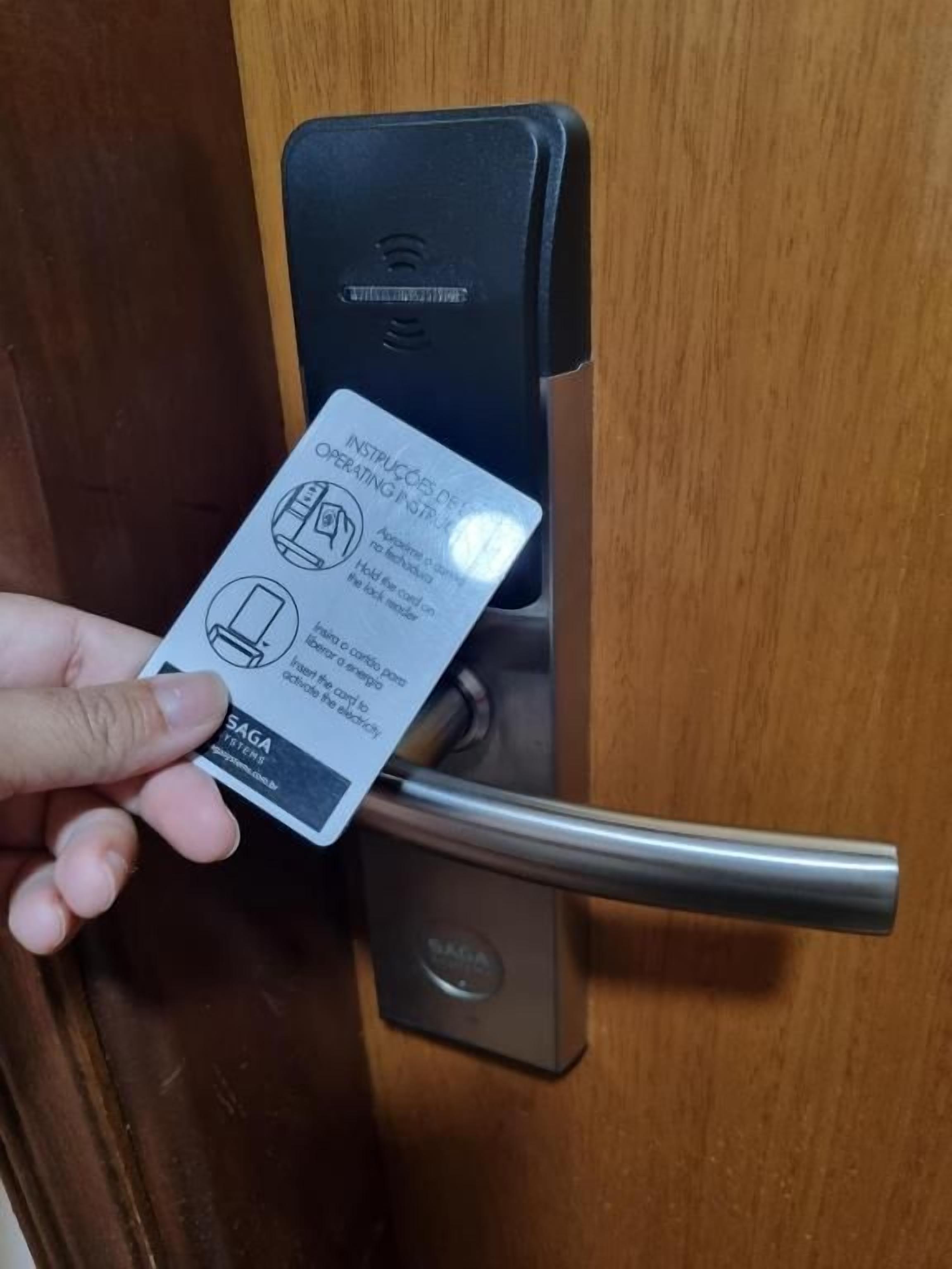Eine Hand hält eine Karte in der Nähe eines Türschlosses mit Schlüsselloch.