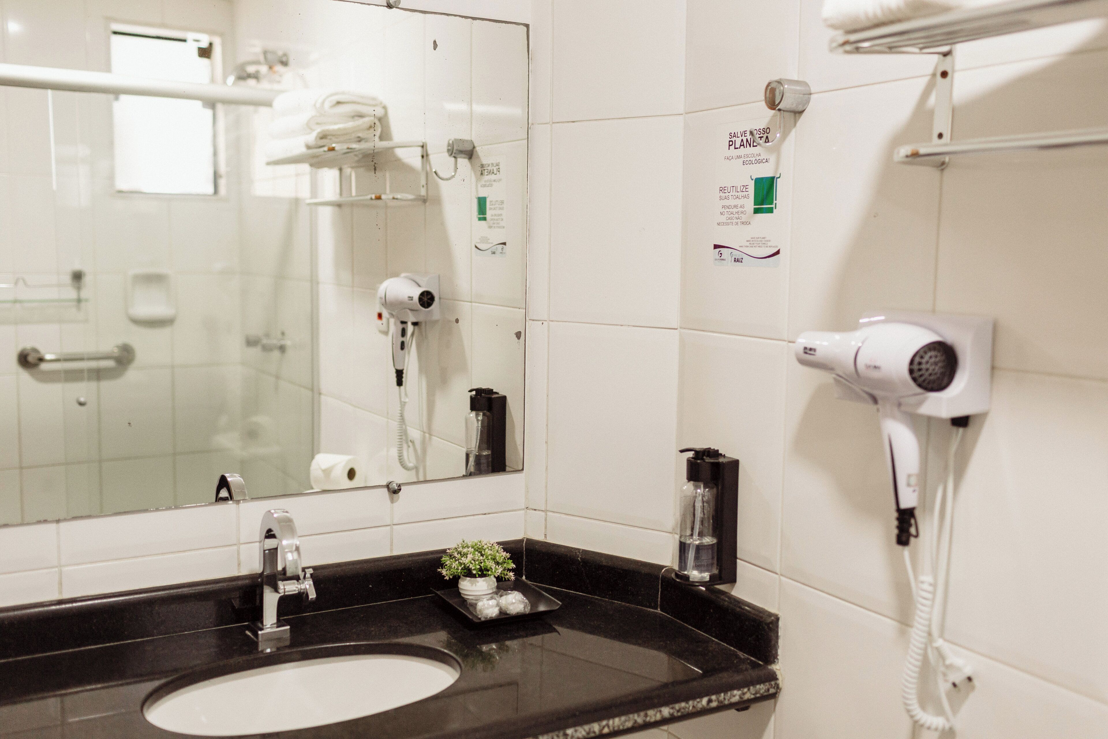 A bathroom with a sink, mirror, hairdryer, and towel rack.