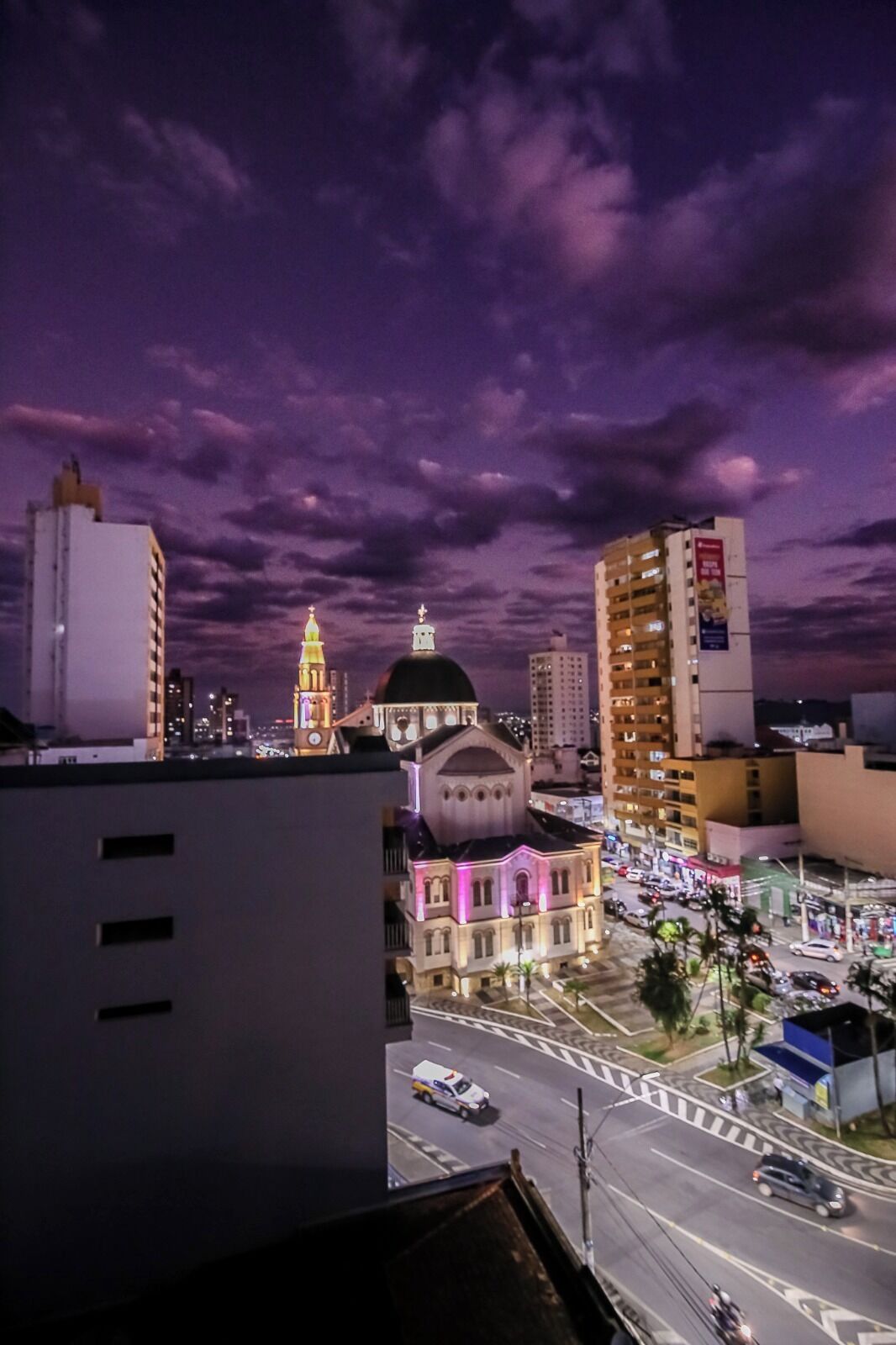 Un paisaje urbano al anochecer con un edificio destacado que presenta una cúpula y un campanario.
