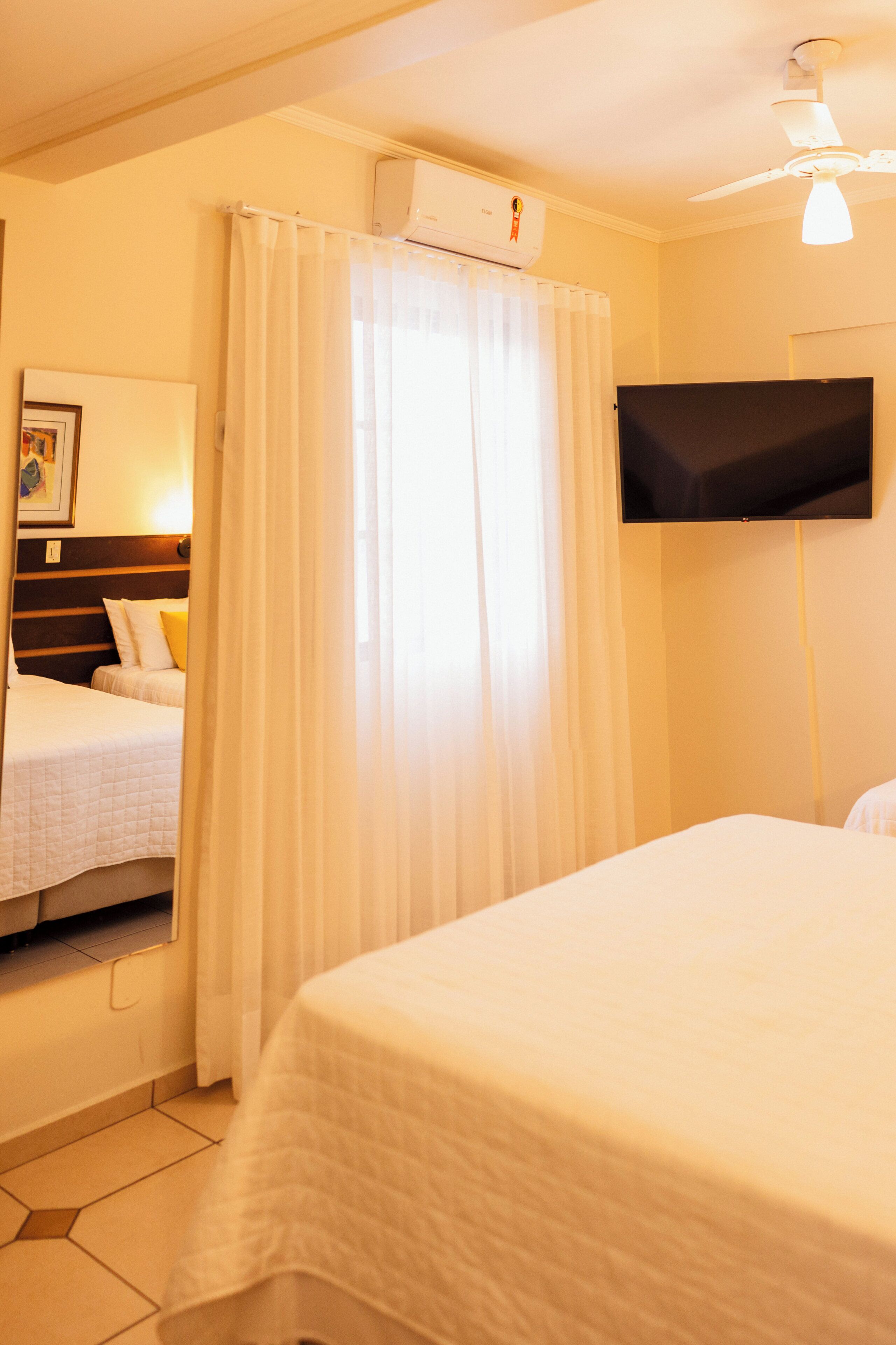 Een hotelkamer met twee bedden, een flatscreen televisie aan de muur en een plafondventilator.