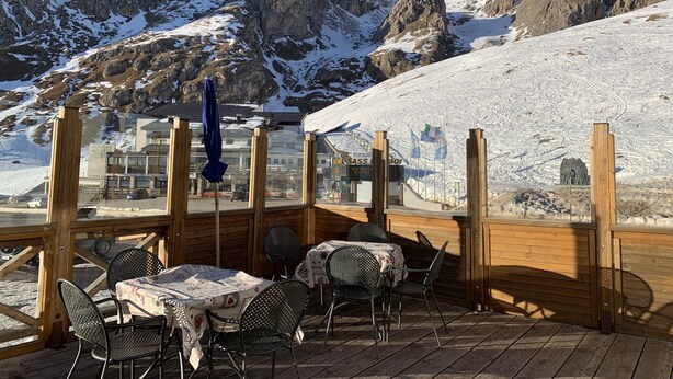 An outdoor seating area with tables and chairs, overlooking a mountainous landscape with rocky cliffs and snow. - Hotel Col Di Lana (Canazei)