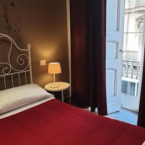 Relax in this inviting room with a comfortable bed, a small table, and a balcony offering a view of the city.