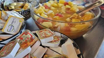 Ein reichhaltiges Buffet mit verschiedenen Speisen, darunter eine Schale Obstsalat, Käse und Beilagen.