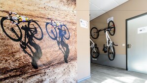 Um corredor com um mural de uma moto de trilha e uma parede branca com duas bicicletas penduradas.
