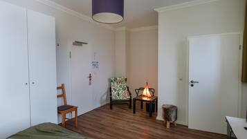 Una habitación con cama, una silla, una mesa con lámpara y un armario.