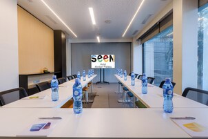 Un salón de conferencias con mesas largas, botellas de agua y un cartel que dice 'SEEN Hotel Abidjan Plateau'.