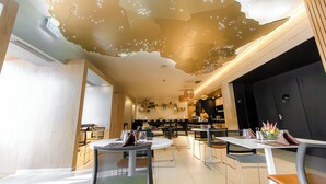 Un interior de restaurante moderno con un diseño de techo único, varias mesas de comedor y una zona de bar.