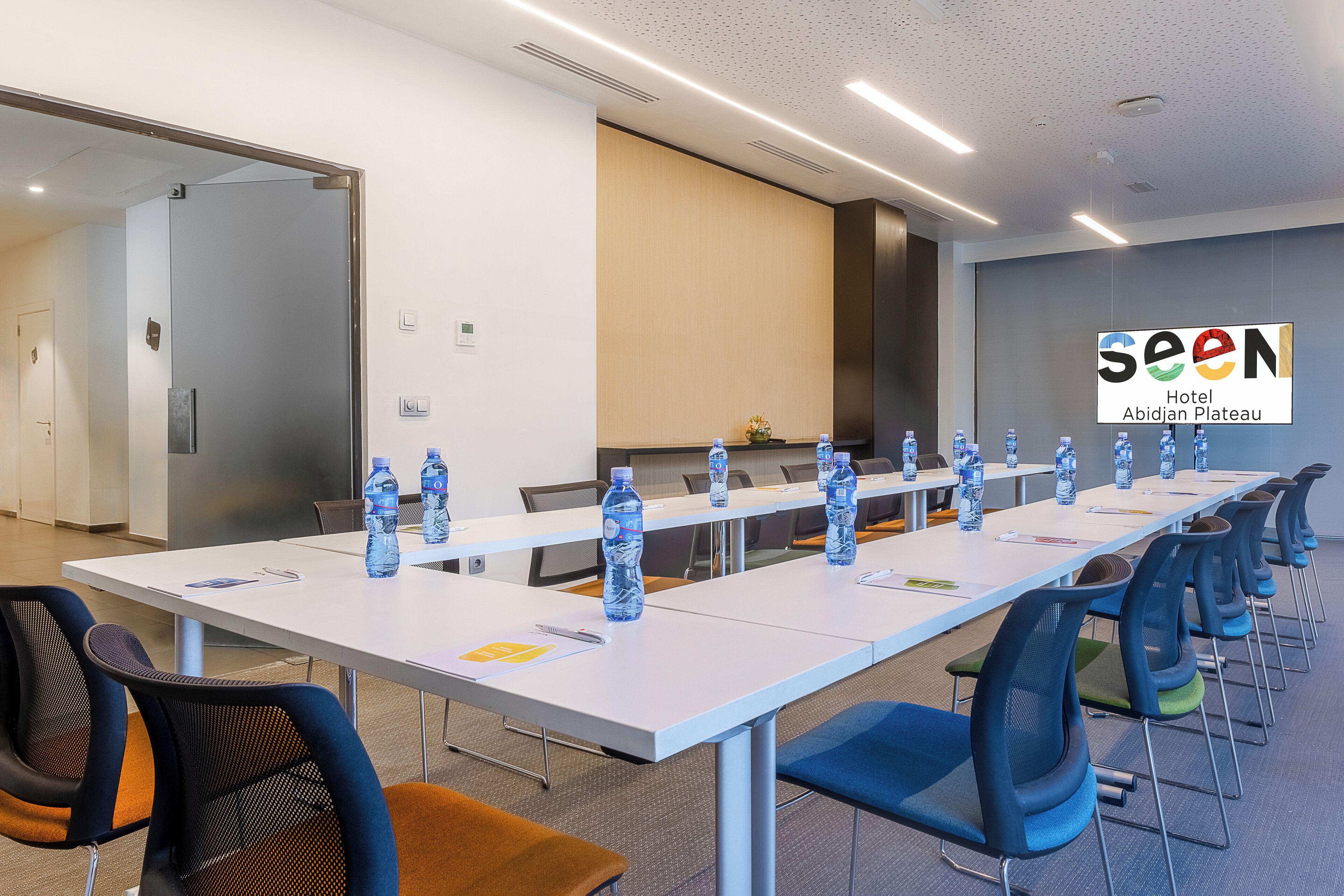 Un salón de conferencias con una larga mesa, sillas y botellas de agua.