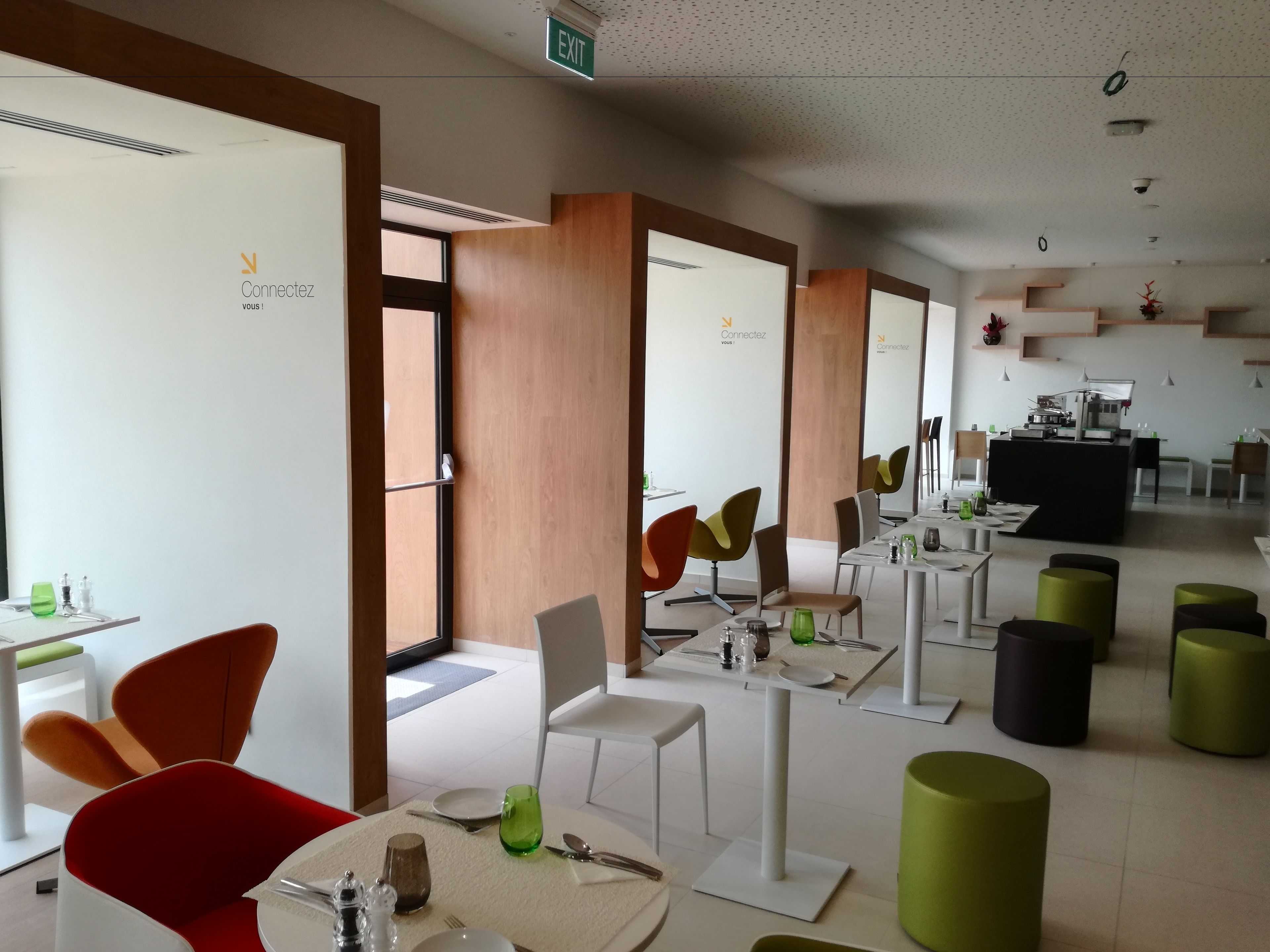 A modern dining area with high tables, chairs, and a buffet station.