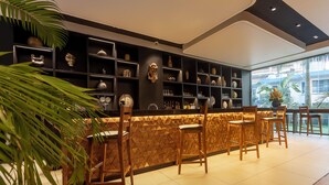 Un área de bar con sillas de madera y estantes llenos de adornos.