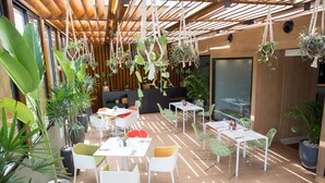 Un espacio interior moderno con suelo de madera, sillas blancas y amarillas, y mesas dispuestas para comer.