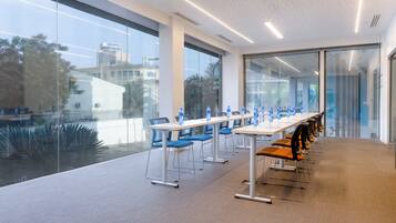 A conference room with glass walls, a long table with chairs, and water bottles on the table.