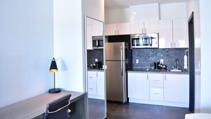 Una cocina moderna con armarios blancos, electrodomésticos de acero inoxidable y encimera negra.