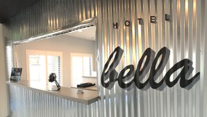 Un mostrador de recepción de hotel con una pared de metal corrugado y el nombre 'bella' en letras grandes.