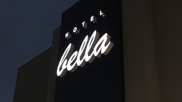 Een hotelsign met de naam 'Hotel Bella' voor een donkere lucht.
