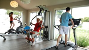 Une salle de sport équipée de tapis de course, d’un rameur et d’une machine de musculation.