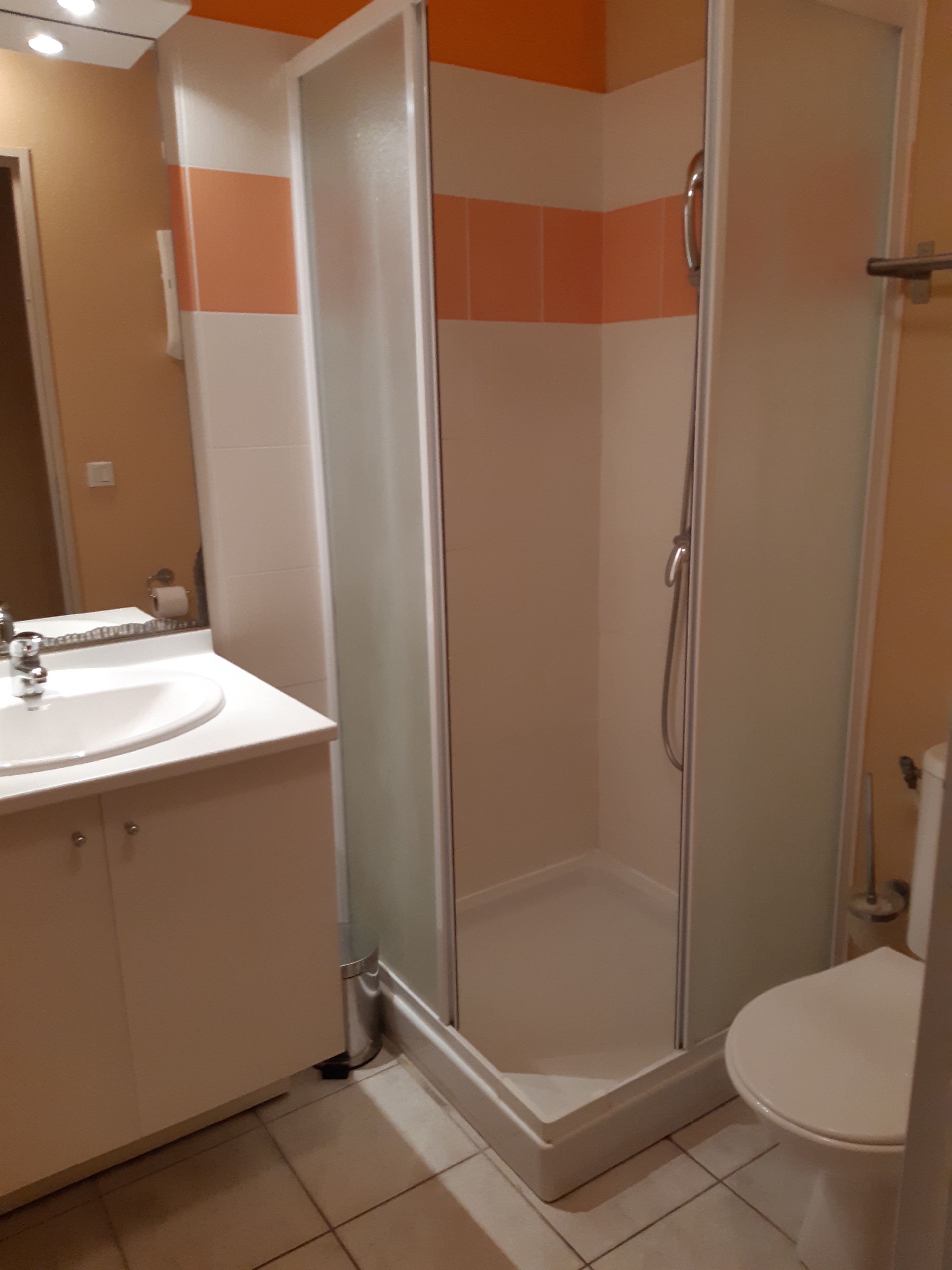 Une salle de bain avec une douche à parois de verre, des toilettes et un lavabo avec des meubles de rangement.